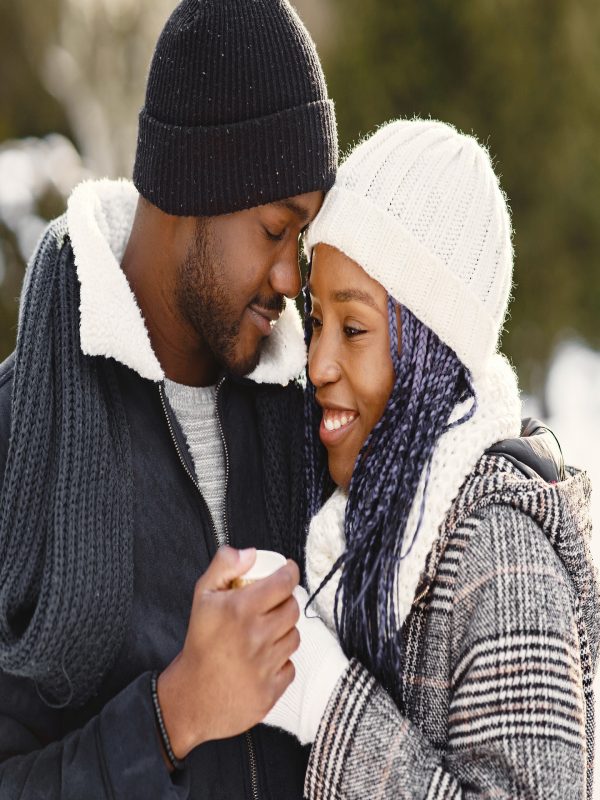 People walks outside. Winter day. African couple with coffee.