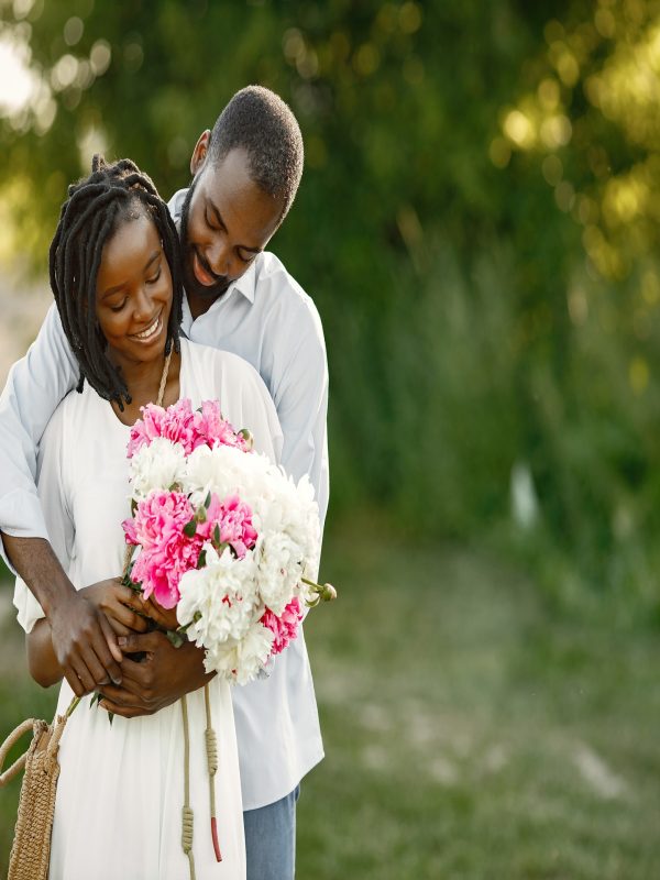 Young African couple in romantic embrace in a field. Young lovers in a field with flowers.